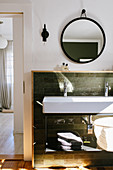 Long sink against green wall tiles with wooden frame
