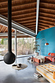 Hängender Kaminofen im modernen Wohnraum mit blauer Wand und Holzbalkendecke