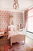 Bed with bed crown in girl's bedroom in shades of pink
