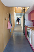 Long hallway with wooden wall and laundry unit in pink