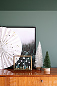 Wintry arrangement of miniature trees in front of picture of forest