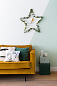 Star of eucalyptus twigs on two-tone wall above sofa
