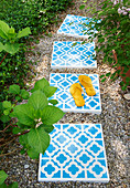 Concrete tiles with ornate pattern used as stepping stones in garden