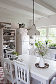 Weißer Tisch mit Stühlen, offenes Regal und Kühlschrank in der Küche