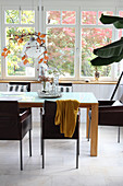 Dark chairs at wooden table in dining room in conservatory