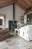 Sofa und Sessel in offenem Wohnraum in ehemaligem Bauernhaus