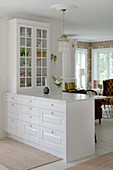 A white breakfast bar with a marble top and a display cabinet