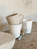 Cups in natural shades on rustic wooden surface next to stone wall