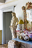 Console table with maritime decorations, mirror and statue next to doorway