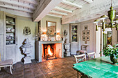 Table with green glazed ceramic top in dining room, fire in fireplace in background