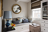 Gold-leaf convex mirror above blue and taupe daybed