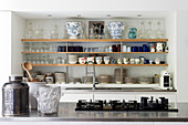 Crockery and glassware storage in kitchen of atelier with five ring hob