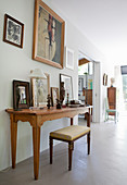 Stool at console table covered with pictures and sculptures in artist's house