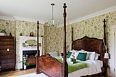 Antique wooden four-poster bed in Regency bedroom with tallboy