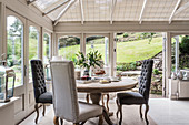 Buttoned dining chairs at table in Victorian conservatory extension