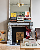 Mirror, books and artistic ornaments on antique mantelpiece