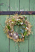 Straw Easter wreath with grape hyacinths, ivy leaves and Easter eggs hung on door