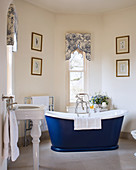Blue, free-standing bathtub in classic bathroom