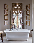 Free-standing bathtub in front of Gothic Revival window in classic bathroom