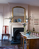 Antique open fireplace in bedroom with pink panelled walls