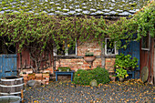 Climber-covered brick cottage with patio area