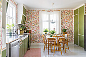 Dining area with floral wallpaper in retro kitchen with green cabinets