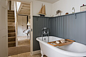 Freistehende Badewanne vor grauer Wandverkleidung im Landhaus