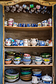 A selection of brightly coloured crockery in an old wooden cupboard
