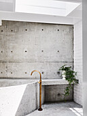 Built-in concrete bathtub in bathroom with partial concrete wall