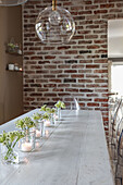 Lanterns on long wooden dining table below glass pendant lamp