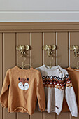 Children's jumpers on wall hooks