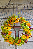 Bottle with umbel umbels and marigold blossoms, behind it an autumn wreath