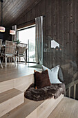 Cushion and fur rug on steps with seat in wooden house