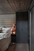 Bedroom with black wardrobe and bed in wooden house