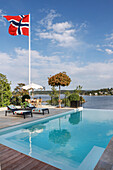 Two sun loungers and Norwegian flag next to swimming pool