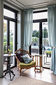 Armchair with scatter cushions and side tables in front of French windows