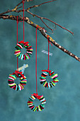 Tiny colourful Christmas wreaths made from felt squares hung from branch