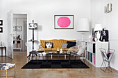 Picture with pink circle above ochre sofa in living room