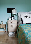 Bedroom with antique bedside cabinet and turquoise wall