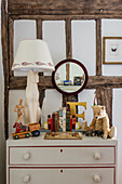 Chest of drawers with toys and table lamp against half-timbered wall