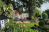 Hillside garden with rambler roses 'Ghislaine de Feligonde' and 'Lykkefund', English rose 'Crown Princess Margareta', catnip, lavender, covered shelf as a workplace