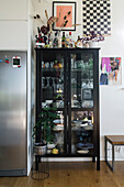 Tableware in black, glass-fronted cabinet in open-plan interior