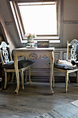Table and chairs in shabby-chic seating area below skylight