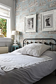 Metal bed with lace scatter cushion in bedroom with toile de jouy wallpaper
