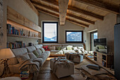 Gemütliche Sofagarnitur, darüber Holzregale im Wohnzimmer mit Dielenboden und Holzdecke
