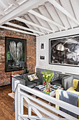 Living room with brick wall, large paintings and open roof structure