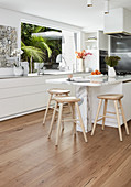 Bar stools at marble counter in white, modern kitchen
