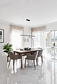 Upholstered chairs around wooden table in white, modern dining room