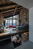 Moderne Lounge in offenem Wohnraum mit Natursteinwänden und Holzbalkendecke