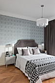 Patterned wallpaper and panelled wainscoting in elegant bedroom